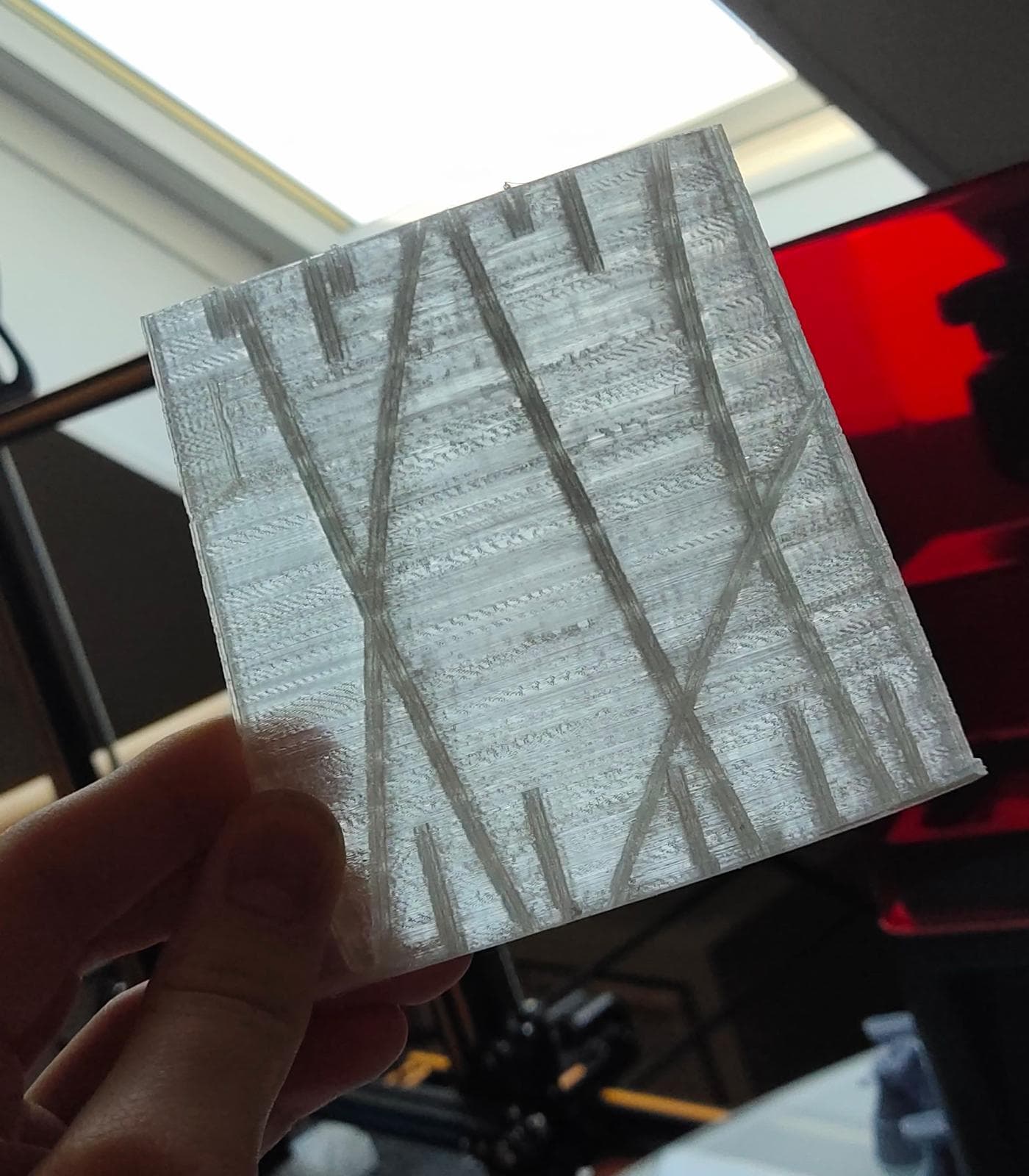 A printed Bf 109 wing section held up against a window, the translucent single-perimeter skin revealing the diagonal internal spine structure