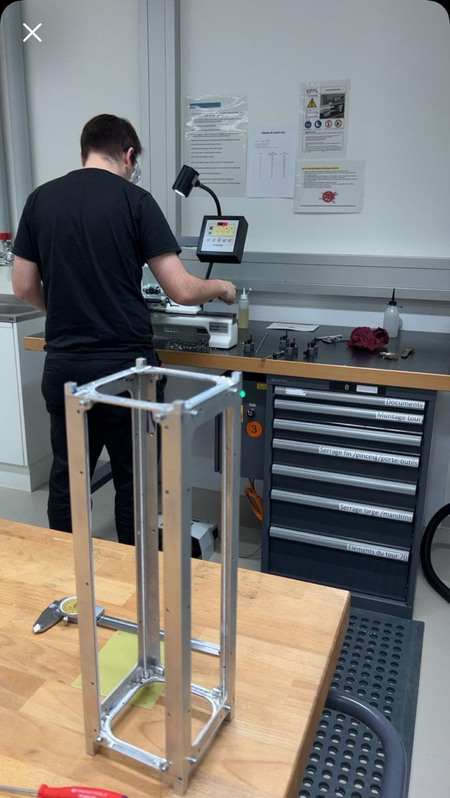 Machining the aluminium primary structure of the CHESS mass model at the EPFL workshop, with the assembled frame on the bench